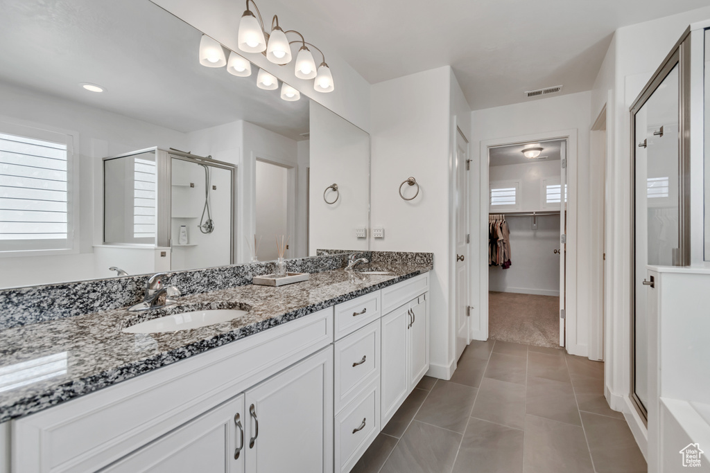 Full bathroom with a stall shower, double vanity, a spacious closet, and tile patterned floors
