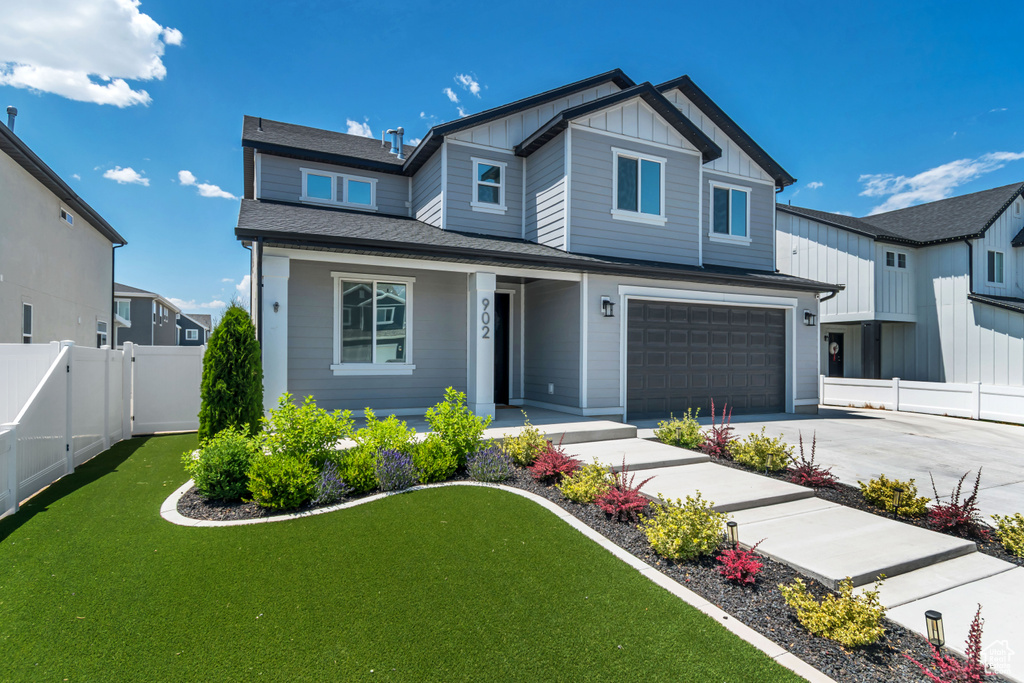 View of front facade with an attached garage, board and batten siding, driveway, and a porch