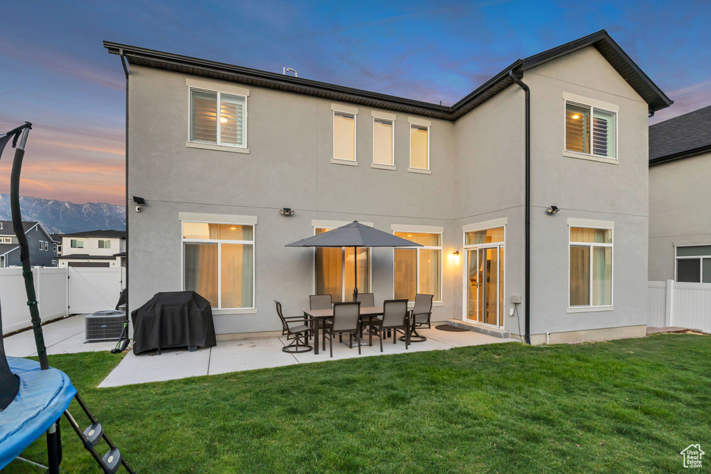 Back of house at dusk featuring stucco siding, a patio, and a fenced backyard
