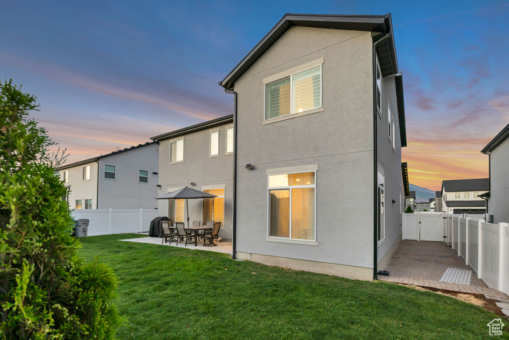 Back of property at dusk with a gate, a fenced backyard, a patio, and stucco siding