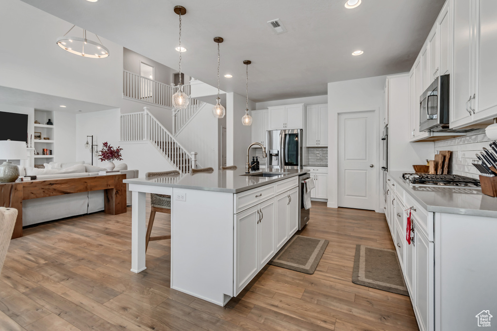 Kitchen with stainless steel appliances, a kitchen breakfast bar, open floor plan, decorative backsplash, and white cabinets