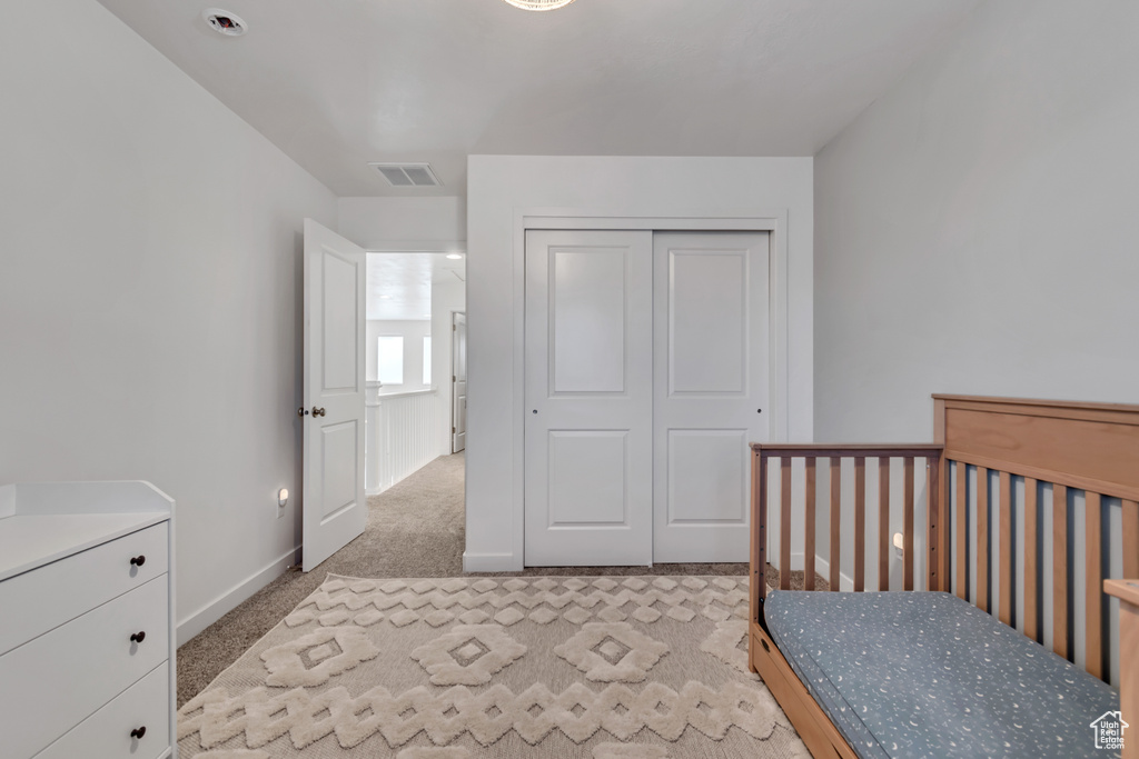 Bedroom featuring light carpet and a closet
