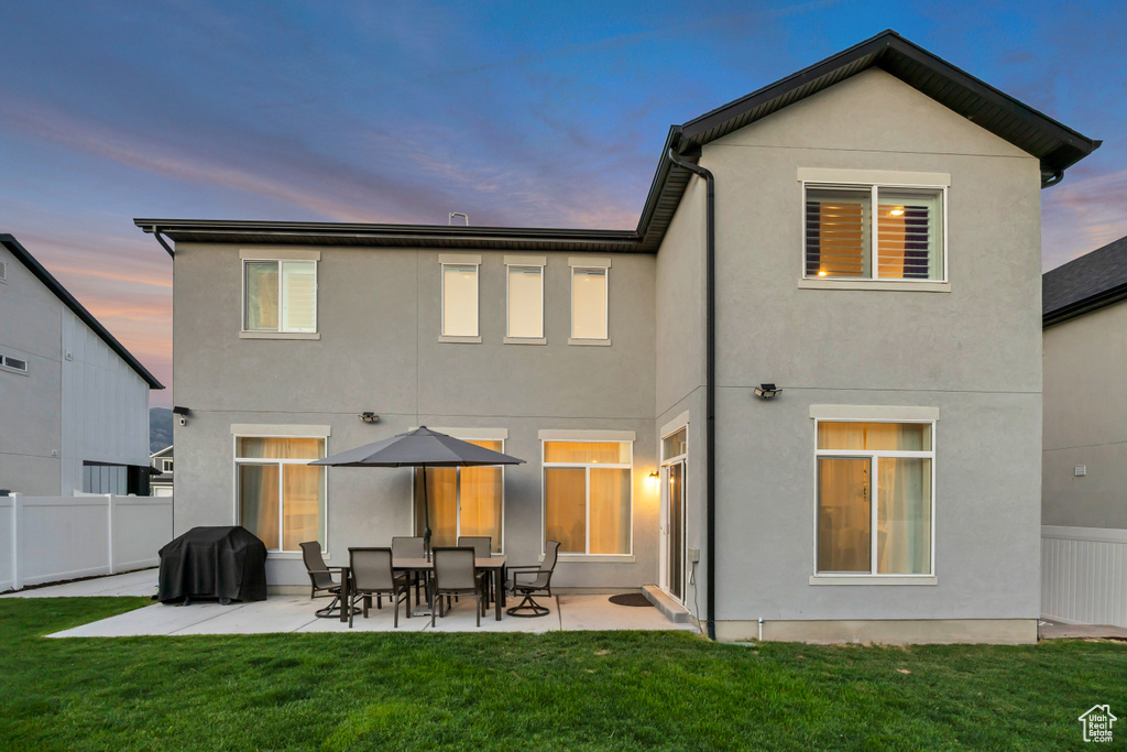 Back of house at dusk featuring stucco siding and a patio