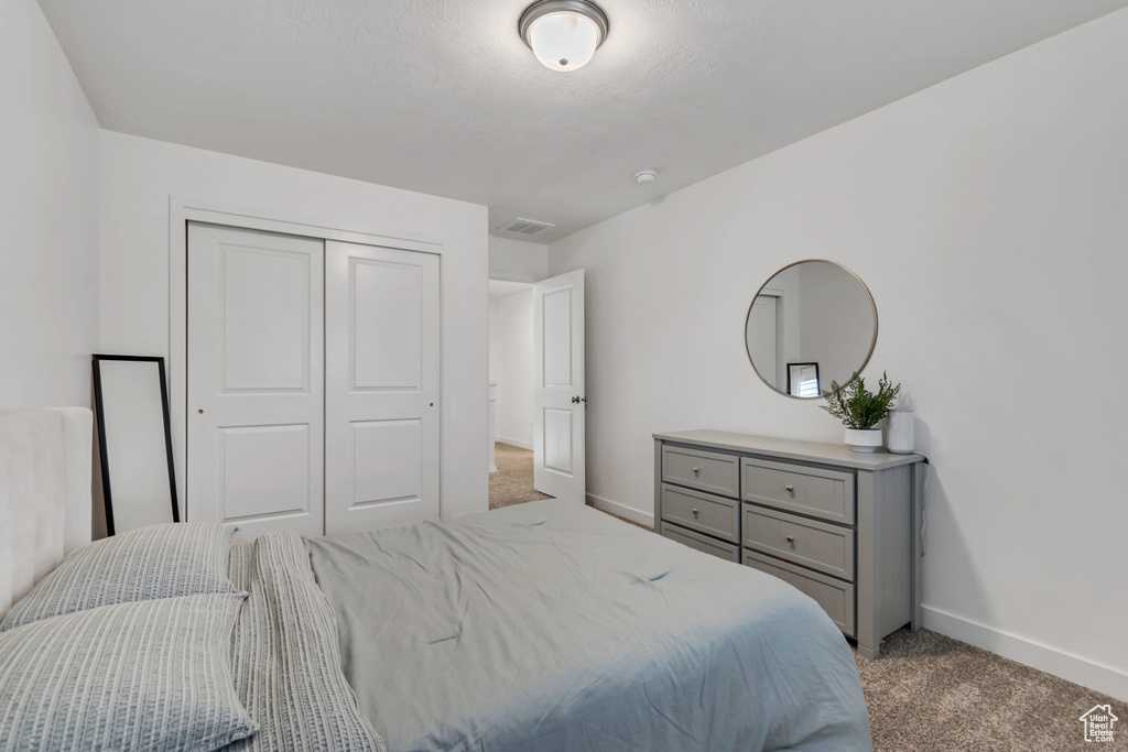 Bedroom with light colored carpet and a closet