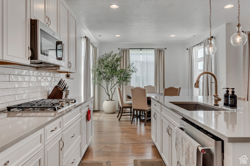Kitchen featuring stainless steel appliances, light wood finished floors, decorative backsplash, light countertops, and recessed lighting