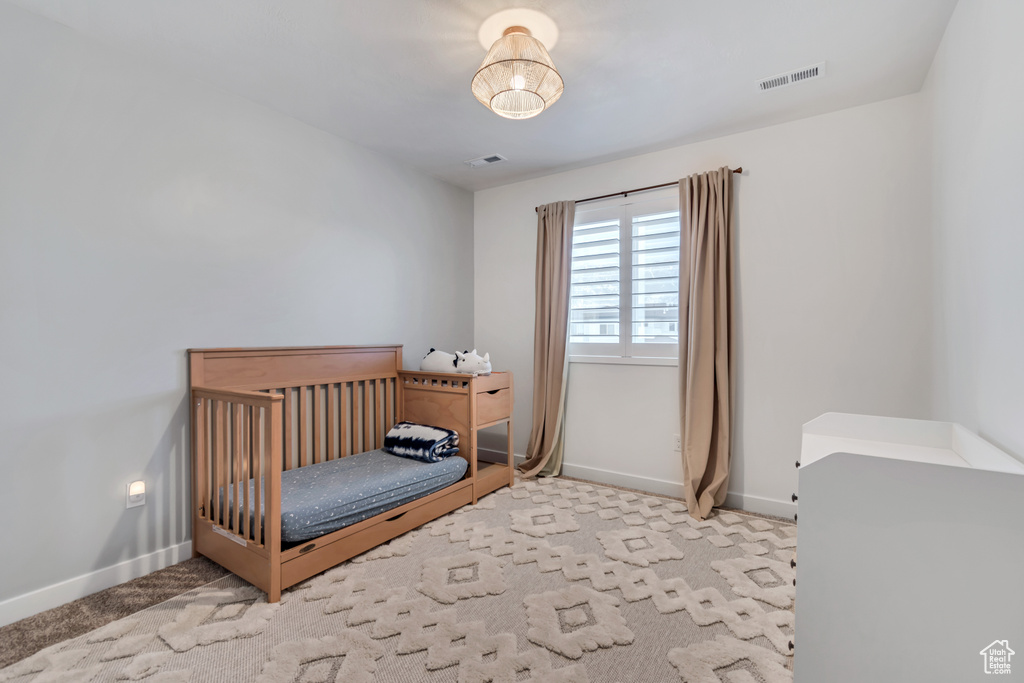Bedroom with carpet and a crib