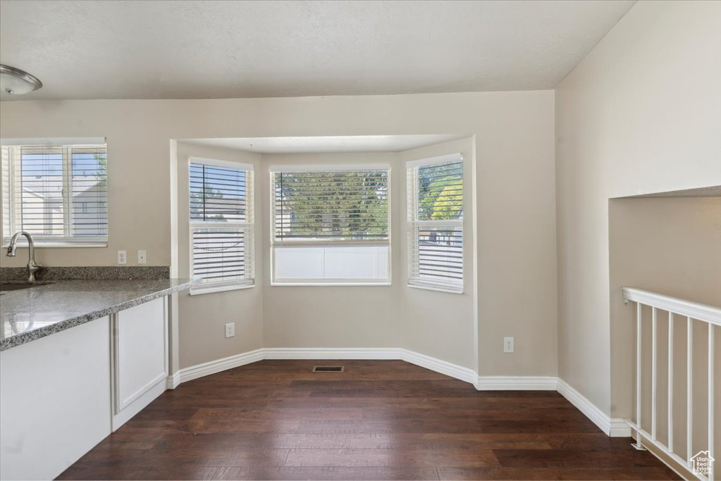 Unfurnished dining area with dark wood-style floors and healthy amount of natural light