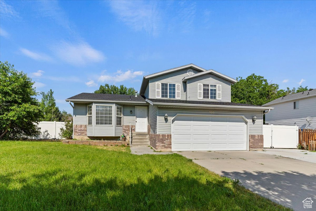 Tri-level home featuring brick siding, a garage, and concrete driveway