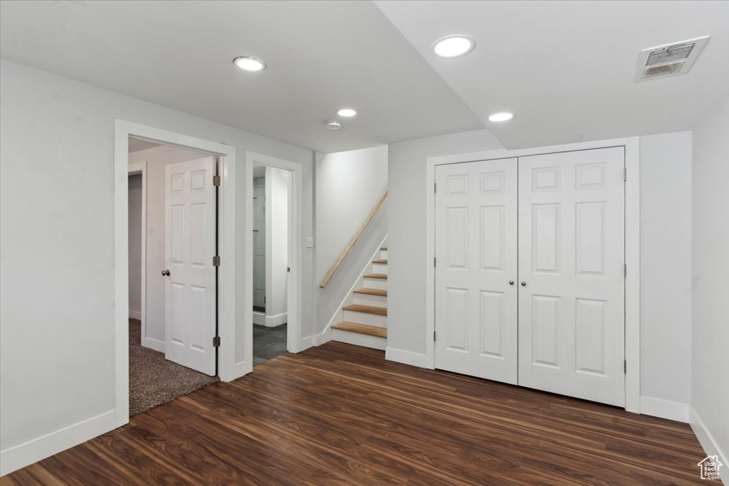 Below grade area featuring dark wood-style flooring, recessed lighting, and stairs