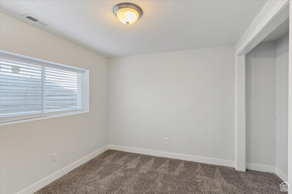 Empty room featuring dark carpet and baseboards