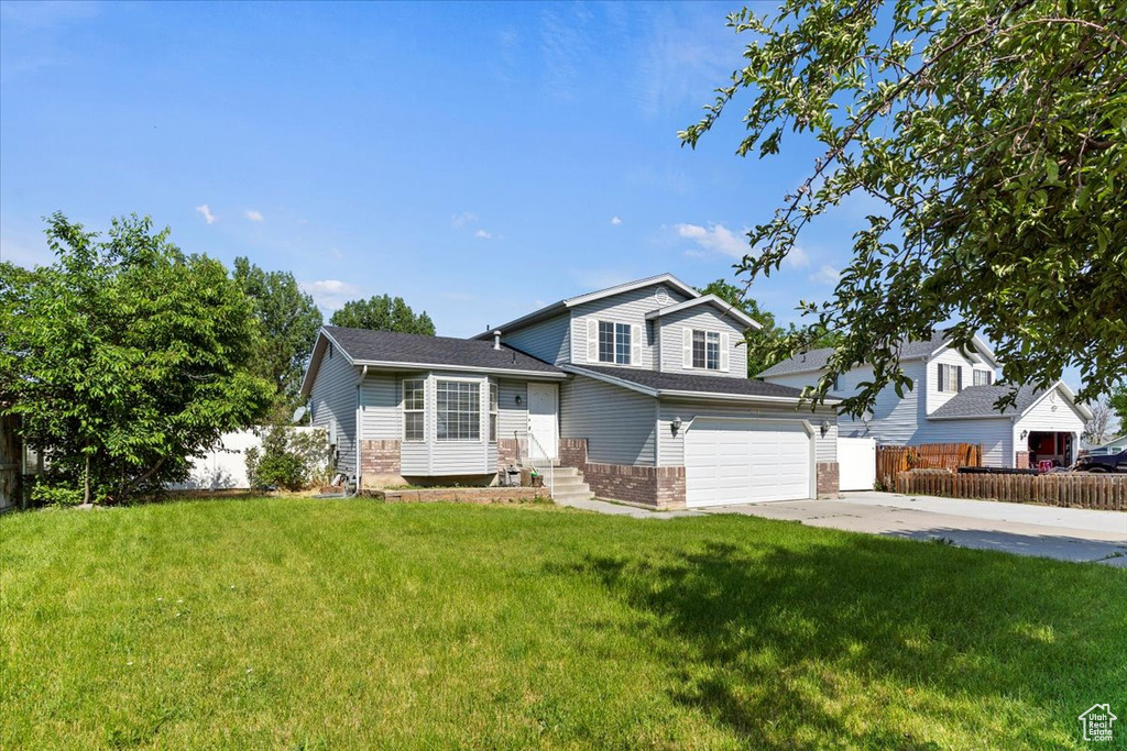 Split level home featuring an attached garage, driveway, and brick siding