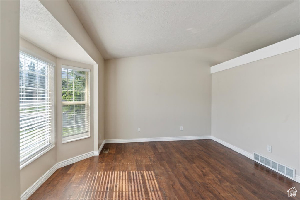 Empty room featuring wood finished floors and vaulted ceiling