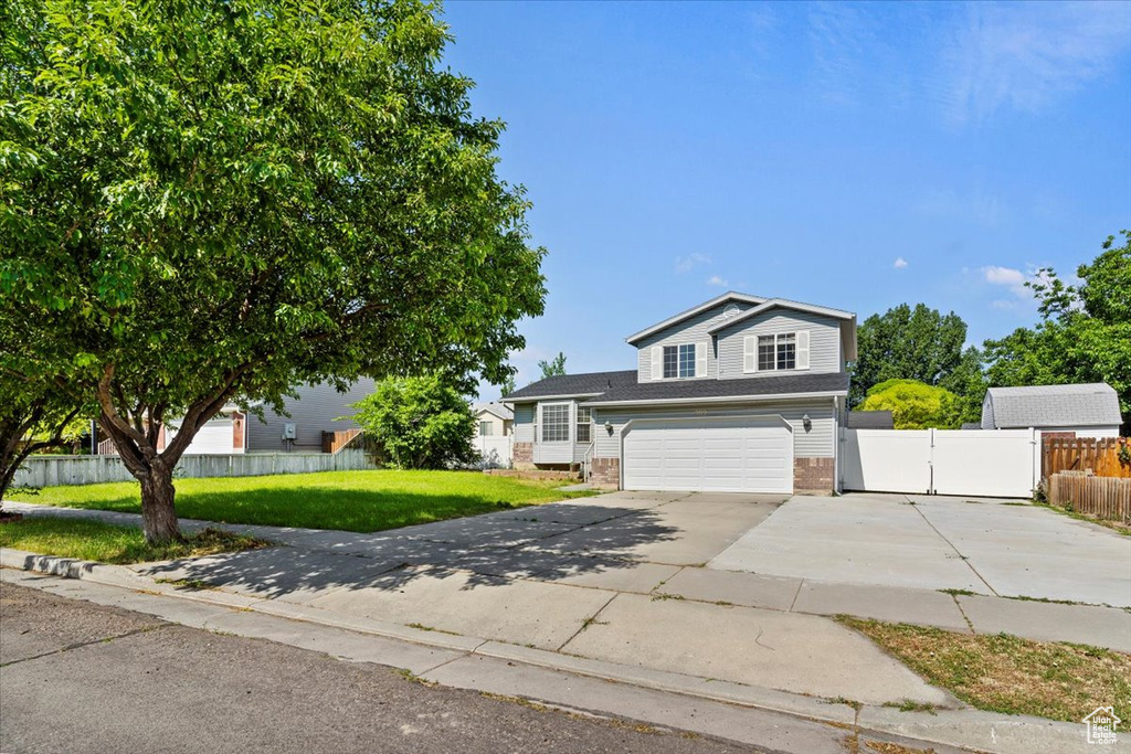 View of front of house featuring concrete driveway, brick siding, a gate, and an attached garage