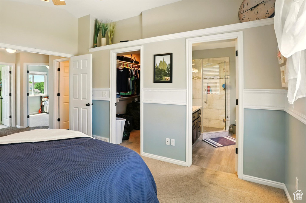 Bedroom with light carpet, a spacious closet, a closet, a wainscoted wall, and connected bathroom