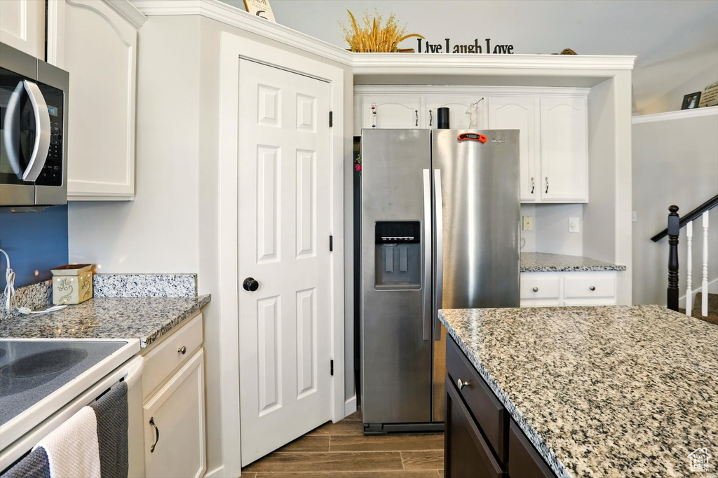 Kitchen with stainless steel refrigerator with ice dispenser, dark wood finished floors, and white cabinets
