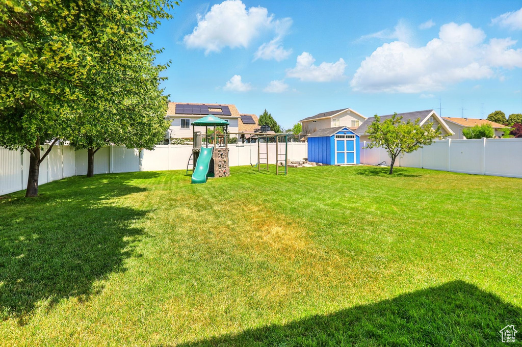 Fenced backyard with a playground and a shed