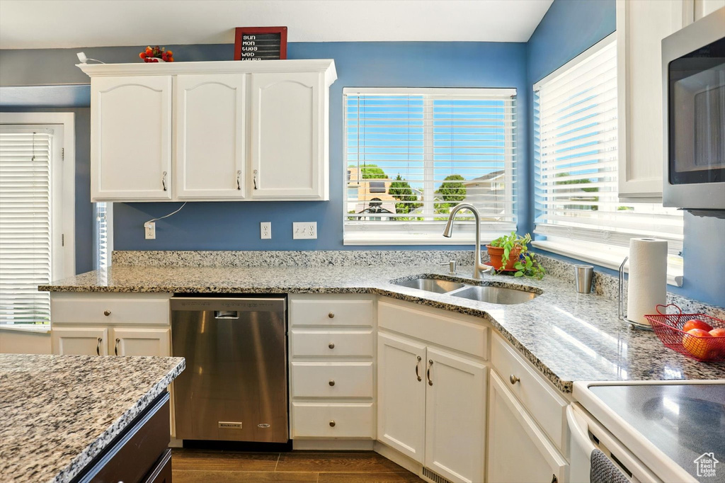 Kitchen with appliances with stainless steel finishes, white cabinetry, and light stone counters