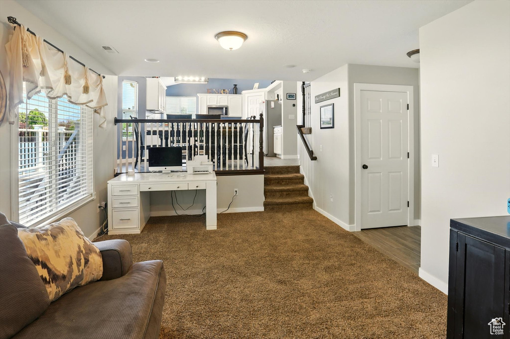 Home office with dark colored carpet and baseboards