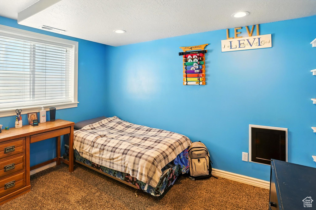 Bedroom with dark colored carpet, a textured ceiling, and recessed lighting