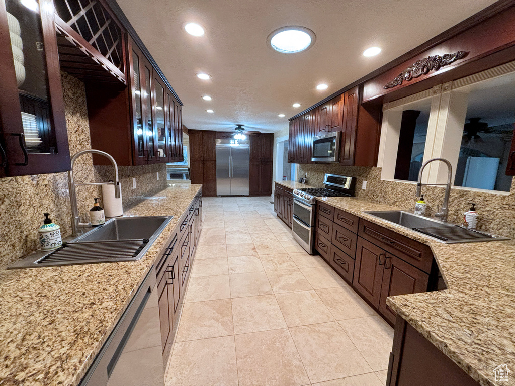 Kitchen featuring stainless steel appliances, recessed lighting, backsplash, a ceiling fan, and light stone counters