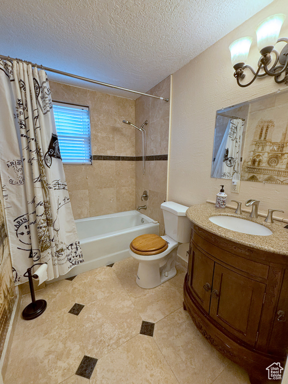 Bathroom featuring vanity, shower / bath combo with shower curtain, a textured ceiling, and a chandelier