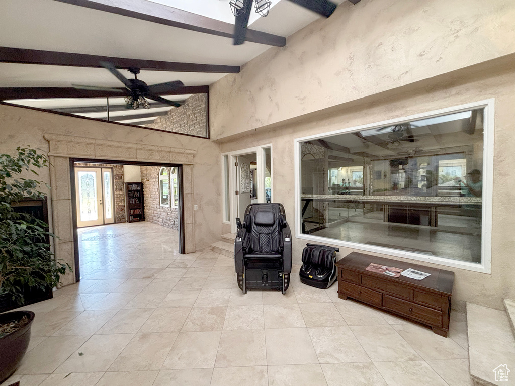 Living area with beamed ceiling, ceiling fan, a high ceiling, and tile patterned flooring