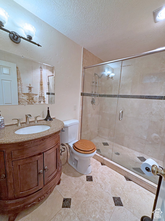Full bath featuring a textured ceiling, a shower stall, and vanity