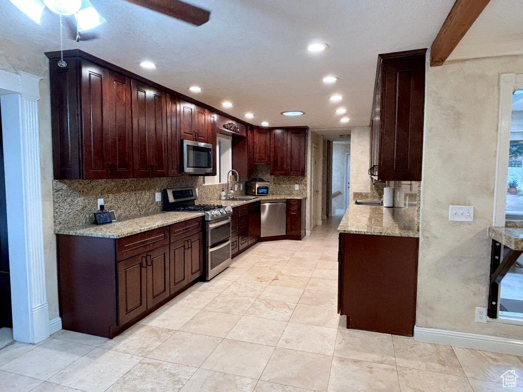 Kitchen featuring appliances with stainless steel finishes, recessed lighting, tasteful backsplash, light stone countertops, and ceiling fan