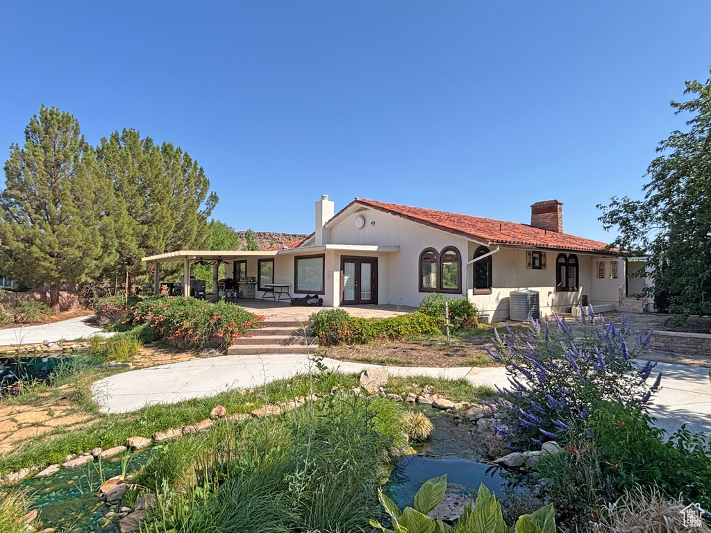 Back of house featuring a chimney, french doors, and stucco siding