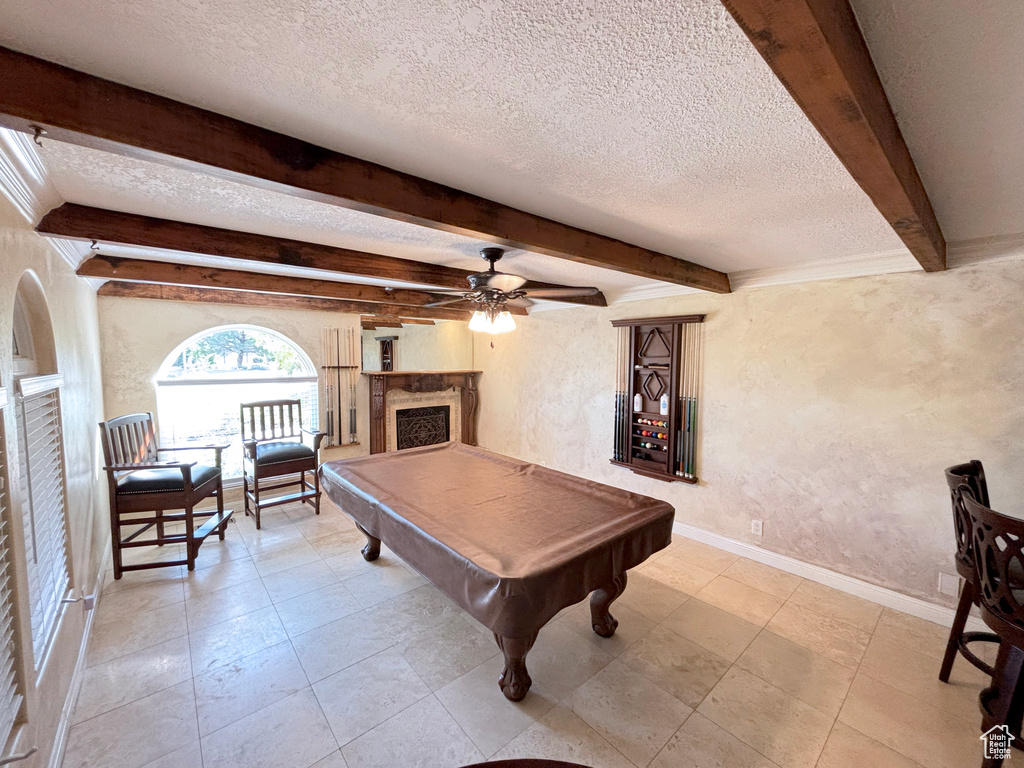 Playroom with a textured wall, pool table, a ceiling fan, beamed ceiling, and a textured ceiling