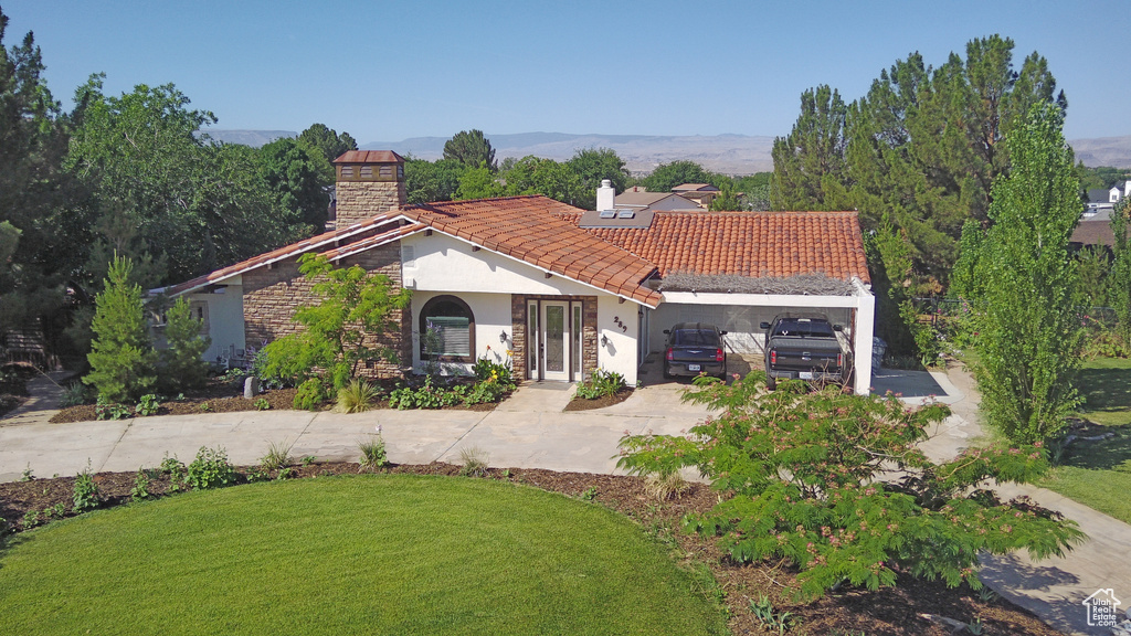 Mediterranean / spanish house with a chimney, stucco siding, concrete driveway, and a front yard