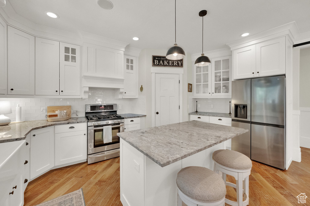 Kitchen featuring appliances with stainless steel finishes, light wood-type flooring, white cabinetry, backsplash, and recessed lighting