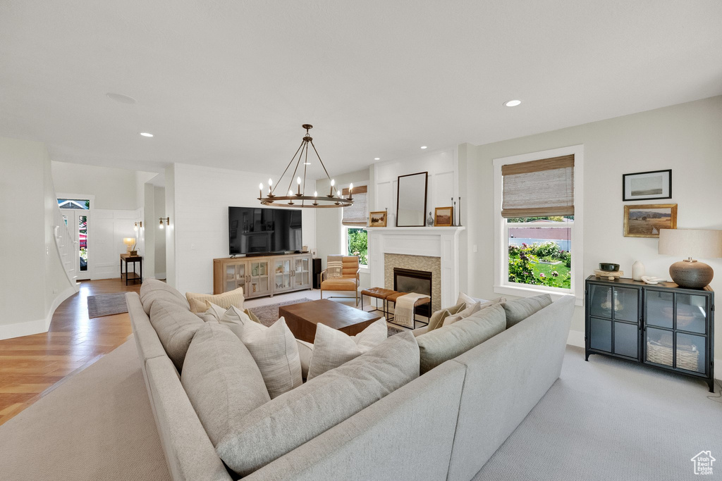 Living room with healthy amount of natural light, a chandelier, a glass covered fireplace, recessed lighting, and light colored carpet