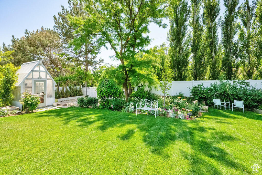 Fenced backyard with a greenhouse and an outbuilding