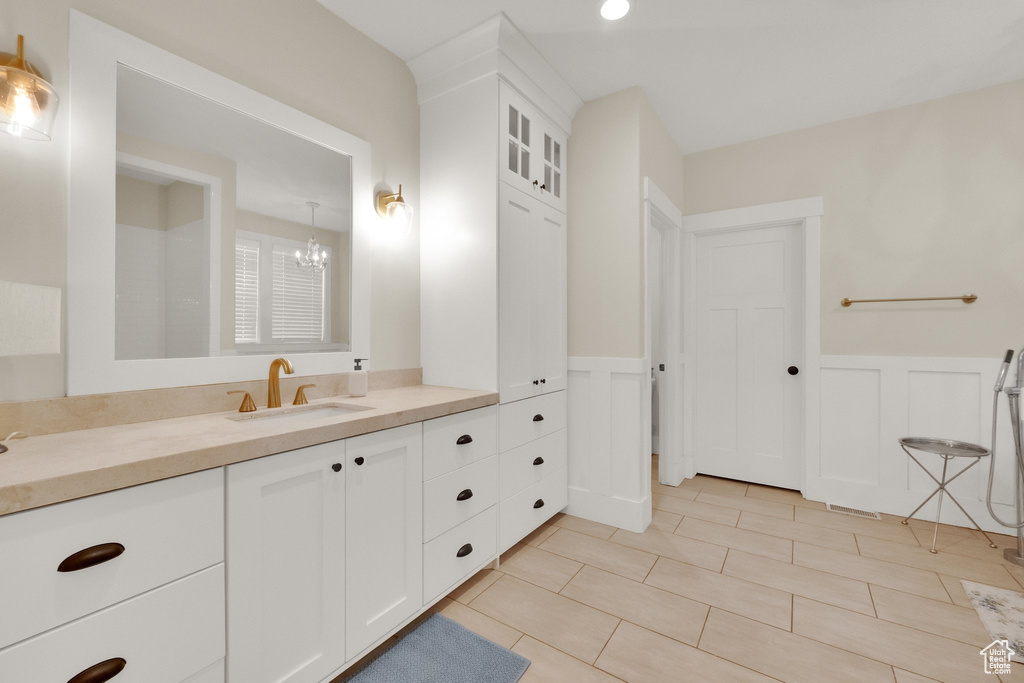 Bathroom with vanity, a wainscoted wall, tile patterned flooring, a decorative wall, and a chandelier