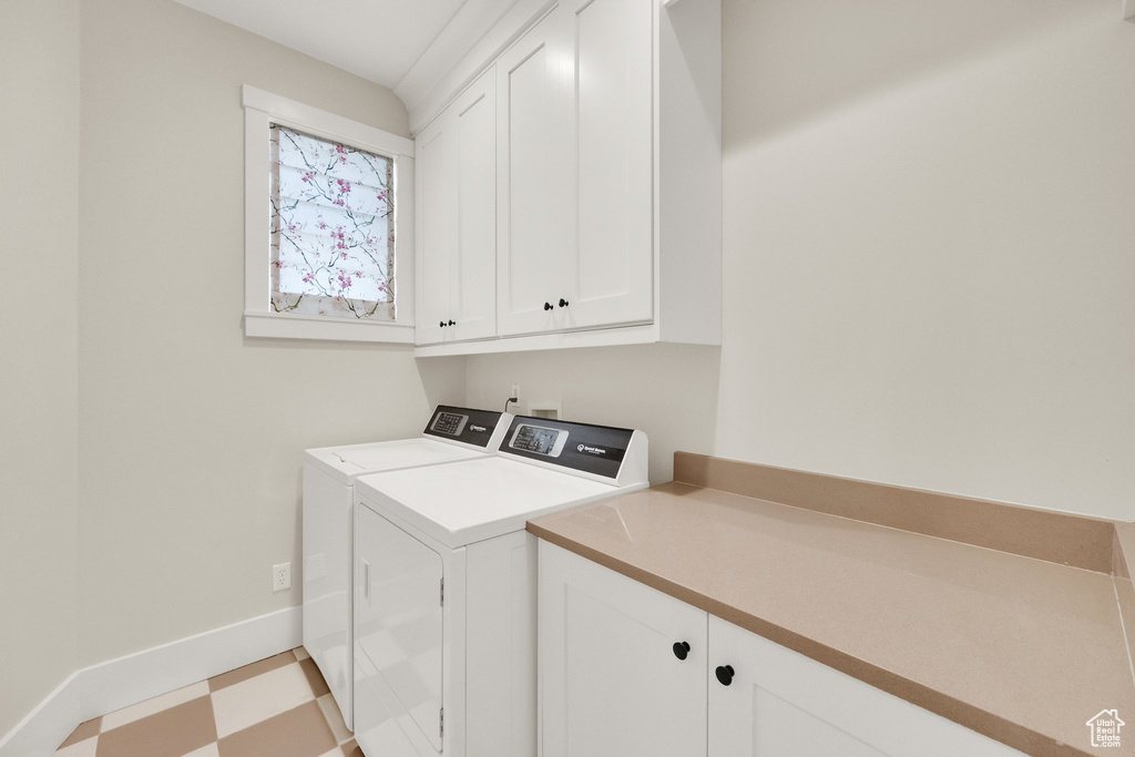 Washroom featuring cabinet space, washer and dryer, and light floors