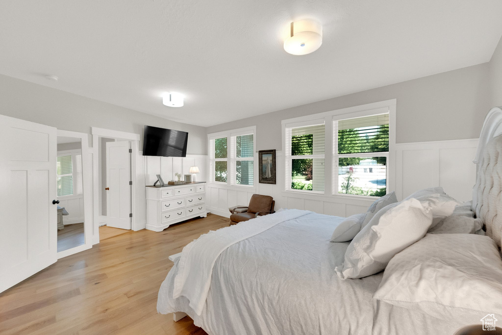 Bedroom featuring a wainscoted wall, light wood-style floors, and a decorative wall