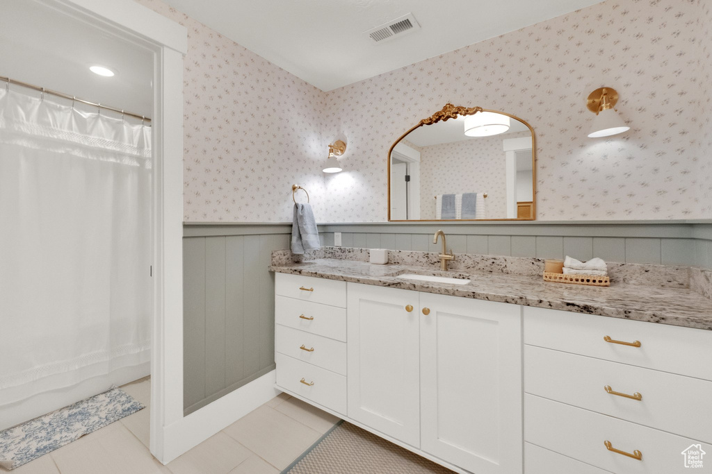 Full bathroom with a wainscoted wall, wallpapered walls, vanity, tile patterned floors, and a shower with curtain