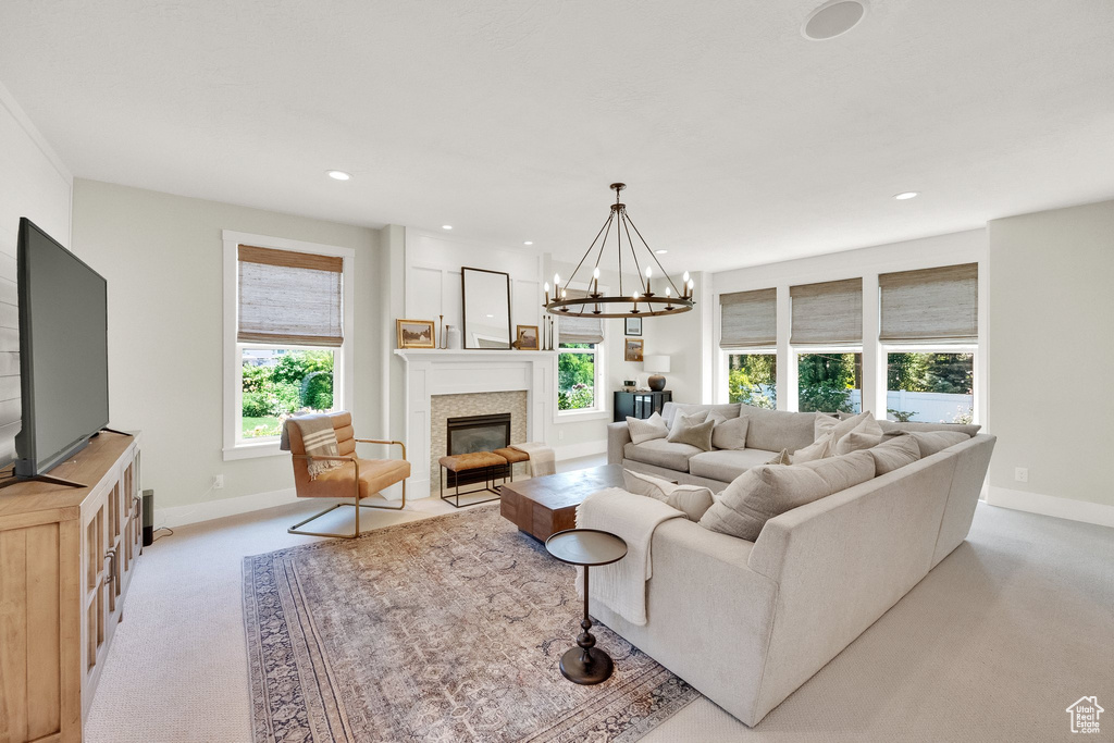 Living area with light colored carpet, plenty of natural light, a fireplace with flush hearth, recessed lighting, and a chandelier