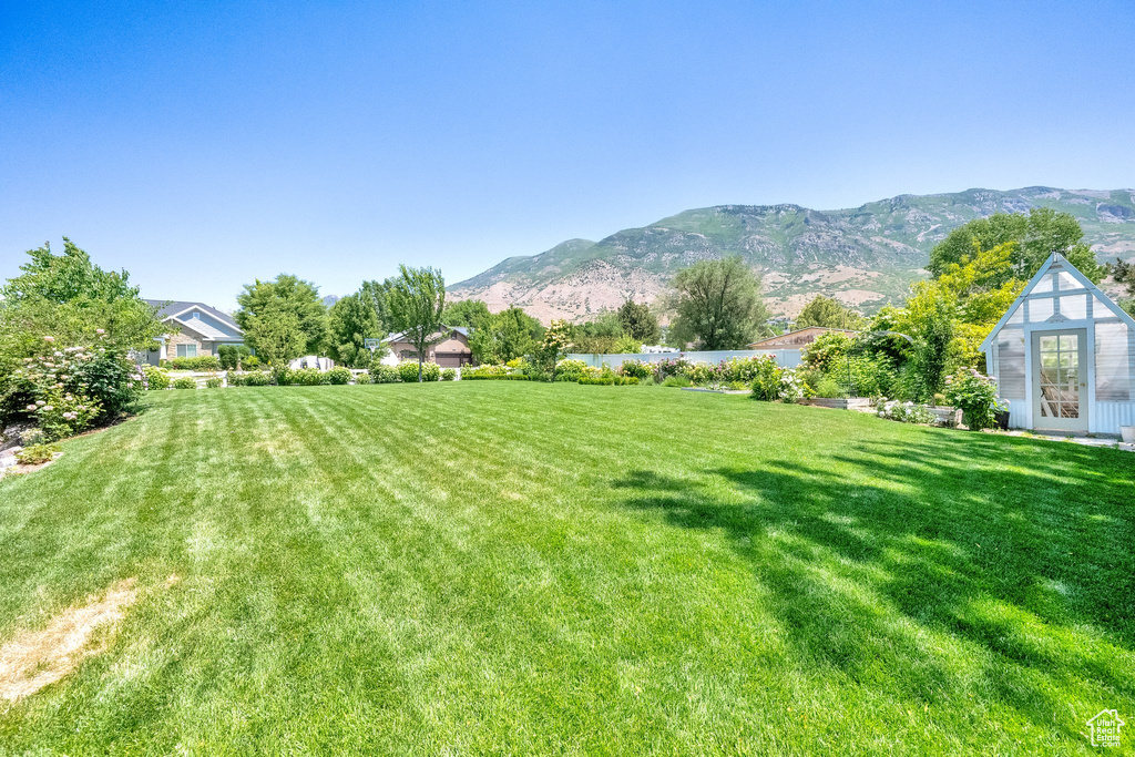 View of green lawn with a mountain view and an outbuilding