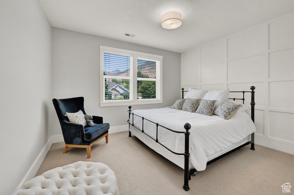 Bedroom featuring light colored carpet and a decorative wall