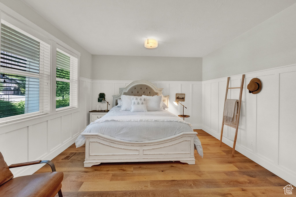 Bedroom featuring a decorative wall, a wainscoted wall, and light wood finished floors