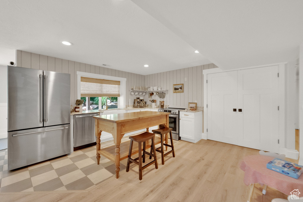Kitchen with appliances with stainless steel finishes, light countertops, light wood-style floors, recessed lighting, and white cabinetry