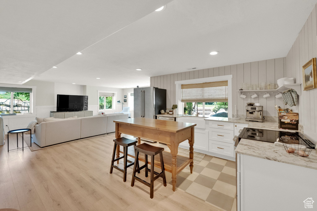 Kitchen with freestanding refrigerator, white cabinets, electric range, light stone counters, and recessed lighting