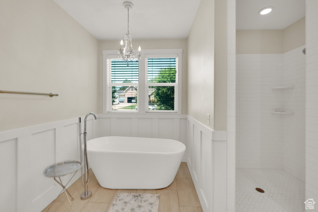 Full bath with a freestanding tub, a wainscoted wall, tile patterned flooring, a chandelier, and a tile shower