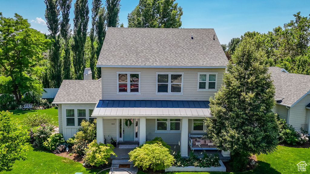 View of front of property with a standing seam roof, a front lawn, a metal roof, a shingled roof, and a chimney