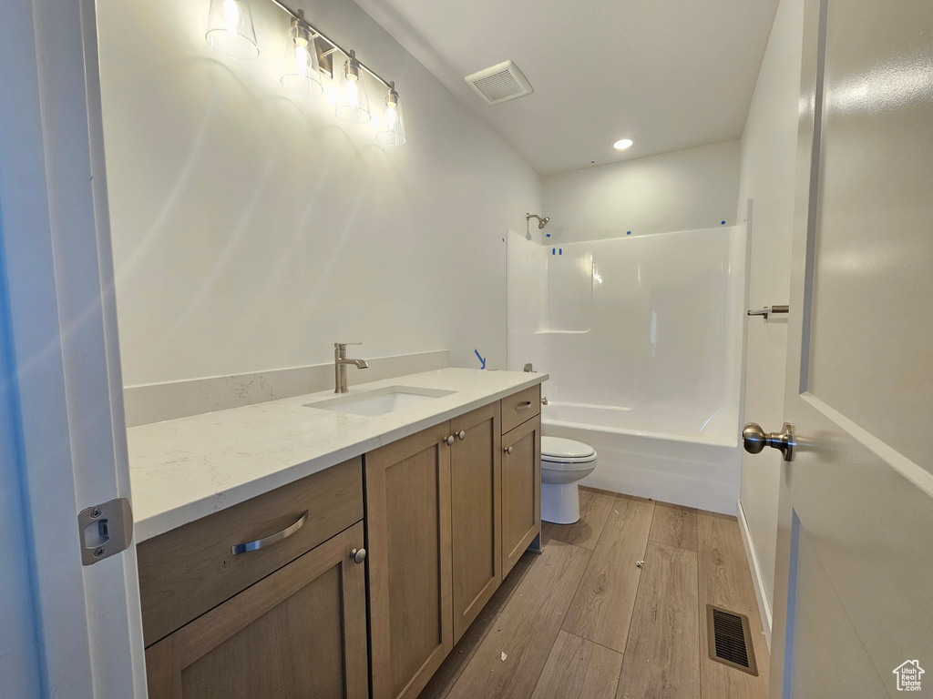 Bathroom with vanity, wood finished floors, shower / washtub combination, and recessed lighting