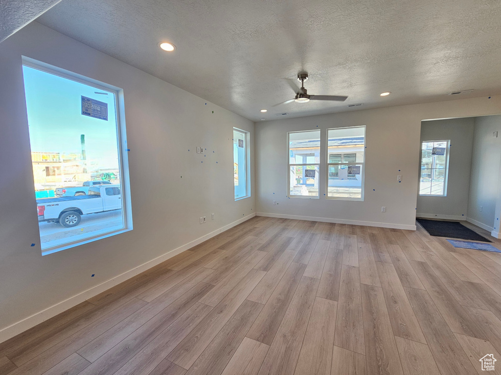Spare room with light wood-style flooring, ceiling fan, a textured ceiling, and recessed lighting