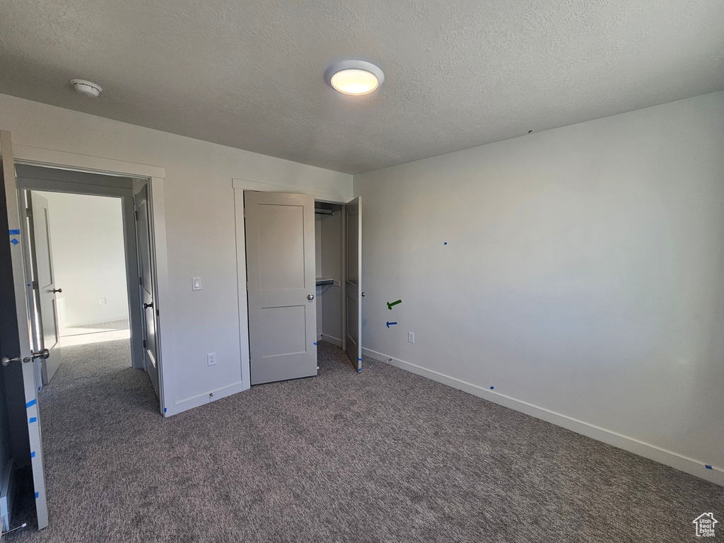 Unfurnished bedroom featuring carpet flooring, a textured ceiling, and a closet