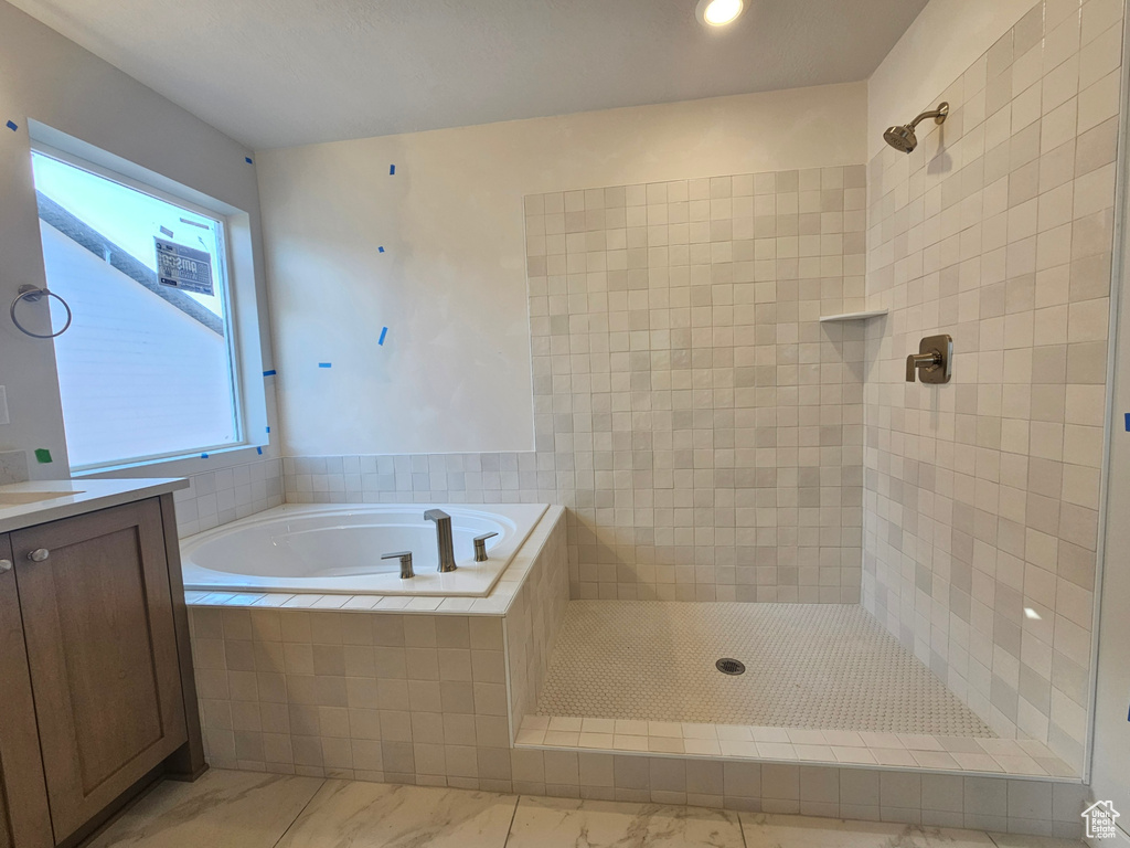 Bathroom with a garden tub, tiled shower, vanity, and marble finish flooring